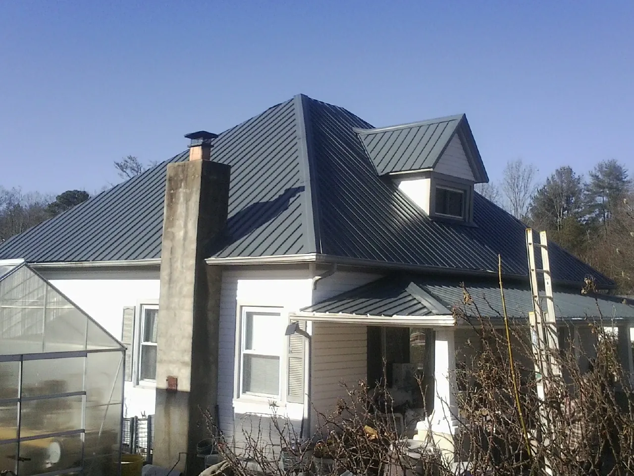 Dark blue standing seam metal roof on a white farmhouse with dormer — Slate & Tile Roof Repair by Roofing Brothers in Lookeba