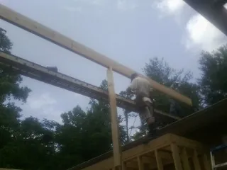Carpenter setting a ridge beam over a new addition frame — Ice Dam Removal by Roofing Brothers in Lookeba