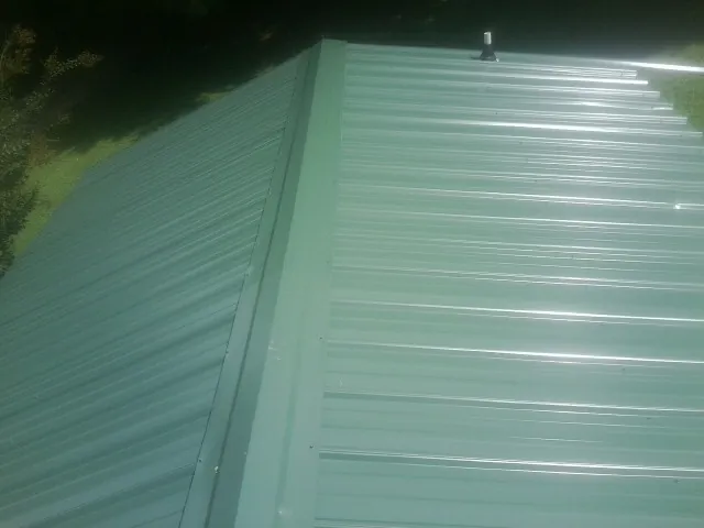 New green metal panels meeting at the ridge of a roof — Flat Roof Repair work by our crew in Lookeba