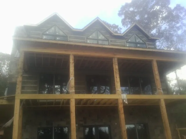 Dormers and porch framing on a large log home under construction — Roof Coating work by our crew in Lookeba