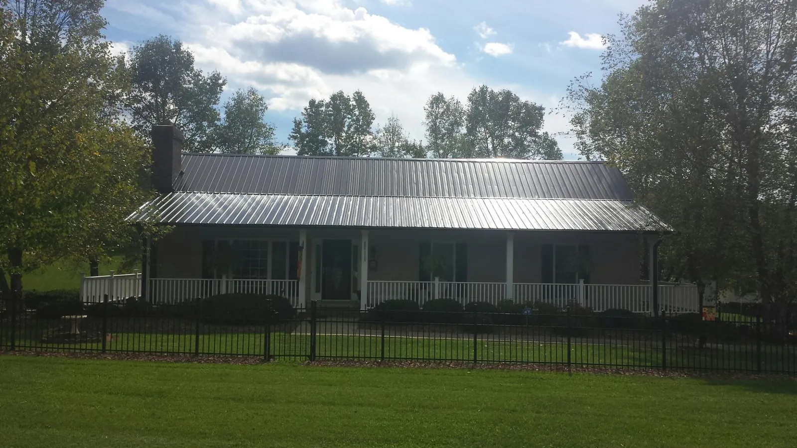Gray metal roof on a brick ranch with a full width front porch — Gutter Guard Installation work by our crew in Lookeba