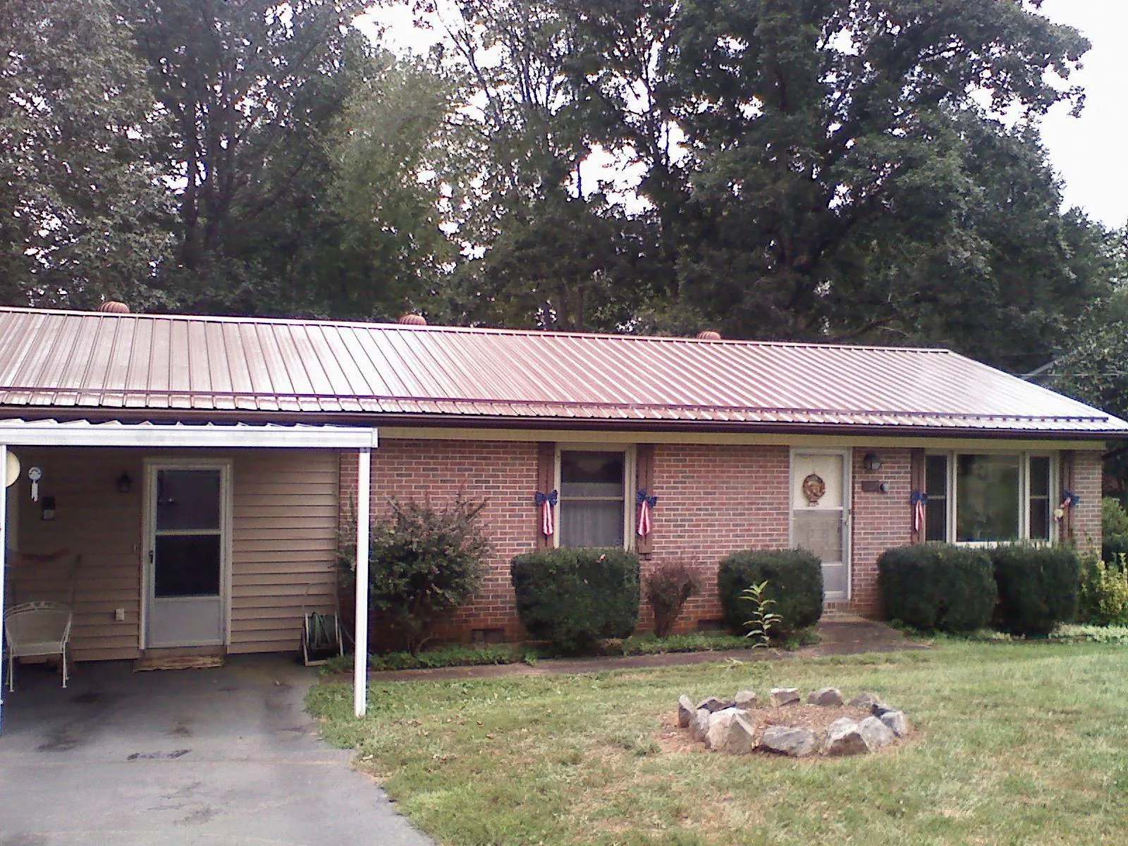 Bronze metal roof and carport on a brick ranch home — Roof Repair work by our crew in Lookeba